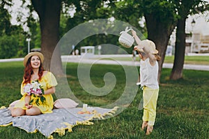 Little cute child baby girl with basket play, have fun and spreading hands with woman in yellow clothes in green park