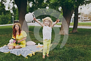 Little cute child baby girl with basket play, have fun and spreading hands with woman in yellow clothes in green park