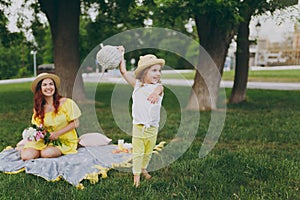 Little cute child baby girl with basket play, have fun and spreading hands with woman in yellow clothes in green park