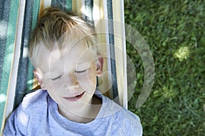 Little cute child blond boy swinging and relaxing on a hammock