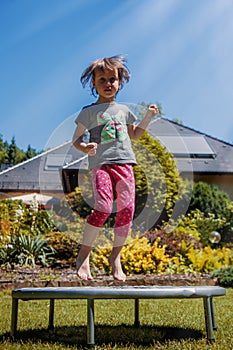 Little cute child girl jumping on a trampoline. Childhood, happiness, joy concept