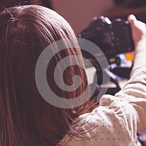 Little cute child girl photographer takes portrait of toy dog with a DSLR camera. Back view