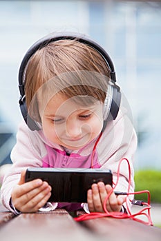 Little cute child girl using mobile phone watching online e-learning video to studying english