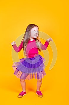 Little cute child kid baby girl 4-5 years old wearing light clothes dancing on yellow background