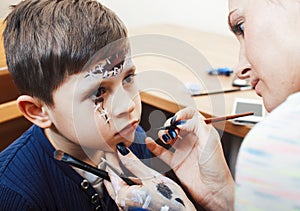 Little cute child making facepaint on birthday party, zombie Apocalypse facepainting, halloween preparing concept