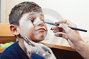 Little cute child making facepaint on birthday party, zombie Apocalypse facepainting, halloween preparing concept