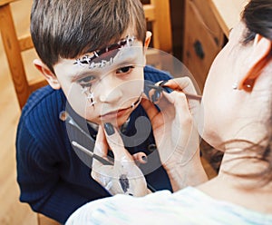 Little cute child making facepaint on birthday party, zombie Apocalypse facepainting, halloween preparing concept