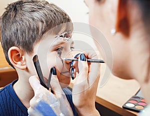 Little cute child making facepaint on birthday party, zombie Apocalypse facepainting, halloween preparing concept