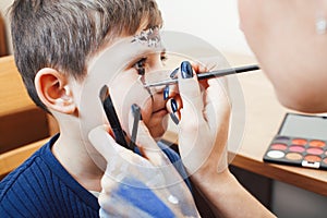 Little cute child making facepaint on birthday party, zombie Apocalypse facepainting, halloween preparing concept