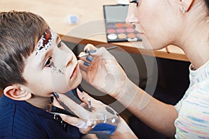 Little cute child making facepaint on birthday party, zombie Apocalypse facepainting, halloween preparing concept