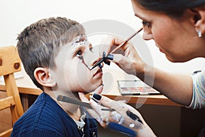 Little cute child making facepaint on birthday party, zombie Apocalypse facepainting, halloween preparing concept