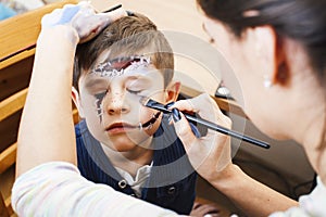 little cute child making facepaint on birthday party, zombie Apocalypse facepainting, halloween preparing concept