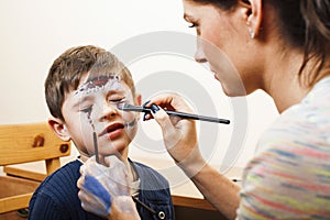 little cute child making facepaint on birthday party, zombie Apocalypse facepainting, halloween preparing concept