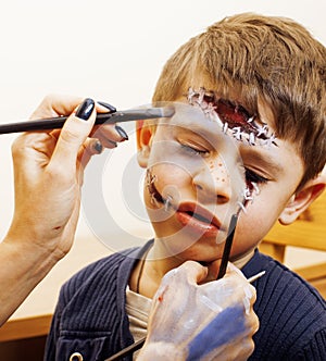 Little cute child making facepaint on birthday party, zombie Apocalypse facepainting, halloween preparing concept