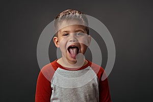 Little cute child. shows his tounge. is isolated on grey background.