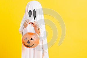 Little cute child with white dressed costume halloween ghost scary he holding orange pumpkin ghost on hand