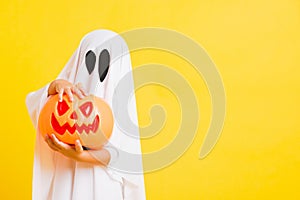 Little cute child with white dressed costume halloween ghost scary he holding orange pumpkin ghost on hand