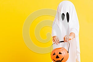 Little cute child with white dressed costume halloween ghost scary he holding orange pumpkin ghost on hand