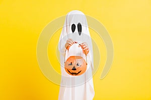 Little cute child with white dressed costume halloween ghost scary he holding orange pumpkin ghost on hand