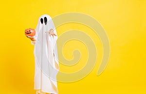 Little cute child with white dressed costume halloween ghost scary he holding orange pumpkin ghost on hand