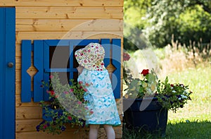 Little cute curios girl looking into the blue window of wooden playhouse