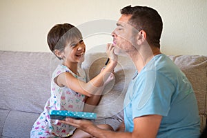 Little cute daughter doing make-up to her father