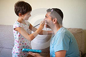 Little cute daughter doing make-up to her father