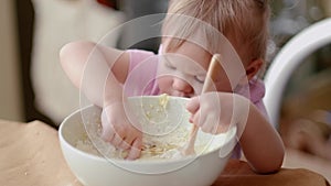 Little cute funny girl licking the dough from her finger helping mother prepare pie cake in kitchen, baking homemade