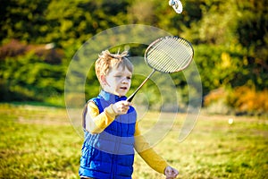 Little cute funny kid boy with badminton racquet playing in park on warm summer spring day. Active outdoors games and leisure for