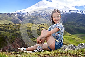 a little cute girl on the background of mountain peaks.