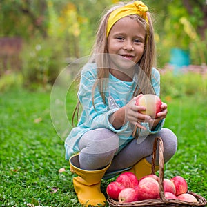 Little cute girl with basket of apples in autumn