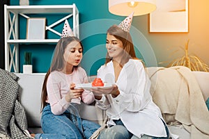 Little cute girl blowing candles on her cake while celebrating birthday party at home with family.