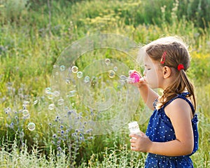 Little cute girl blowing soap bubbles