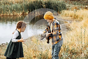 Little cute girl and boy catching a fish in the lake, river or pond. Funny kid wants to hold a fish in hands