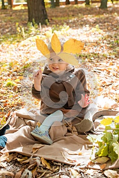 Little cute girl in a brown autumn coat in a sunny autumn park among yellow leaves. Autumn walk in the park