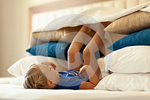 Little cute girl built impromptu fort castle, house out of pillows and blankets on bed. Children handmade tent lodge photo