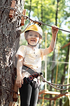 Little cute girl child having fun at adventure park. Kids climbing in a rope park. Children summer activity