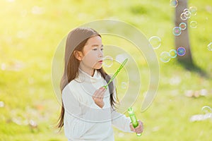 Little cute girl child having fun and enjoying outdoor play blowing soap bubbles