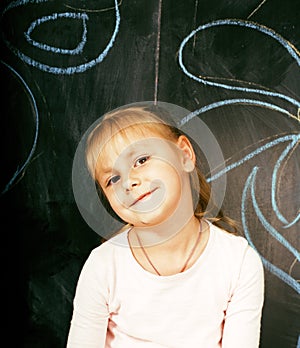 Little cute girl in classroom at blackboard writing smiling, preschooler from back alone, lifestyle people concept