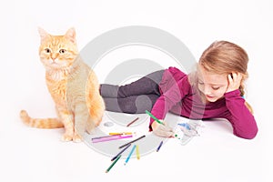 Little cute girl with colored pencils and red cat lying on the floor