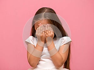 Little girl covers her face with her hands