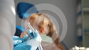 Little cute girl in the dentist`s office does not want to be treated, resisting and closing her mouth with her hands