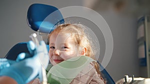 Little cute girl in the dentist`s office does not want to be treated, resisting and closing her mouth with her hands