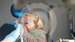 Little cute girl in the dentist`s office does not want to be treated, resisting and closing her mouth with her hands