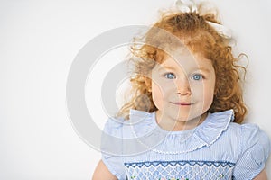 Little cute girl in a dress with redhead. The child is 2 years old.
