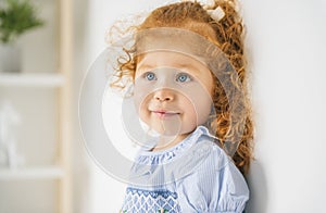 Little cute girl in a dress with redhead. The child is 2 years old.