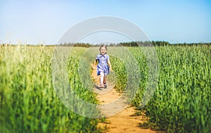 Little girl in a dress runs across the field on a sunny day