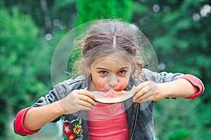 Little cute girl eating a juicy watermelon in the garden. Children eat fruit outdoors. Healthy food for children