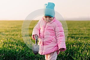 Little cute girl in the field digging the ground with a shovel