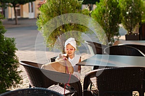 Little cute girl with french bulldog in a chair on the terrace of a cafe